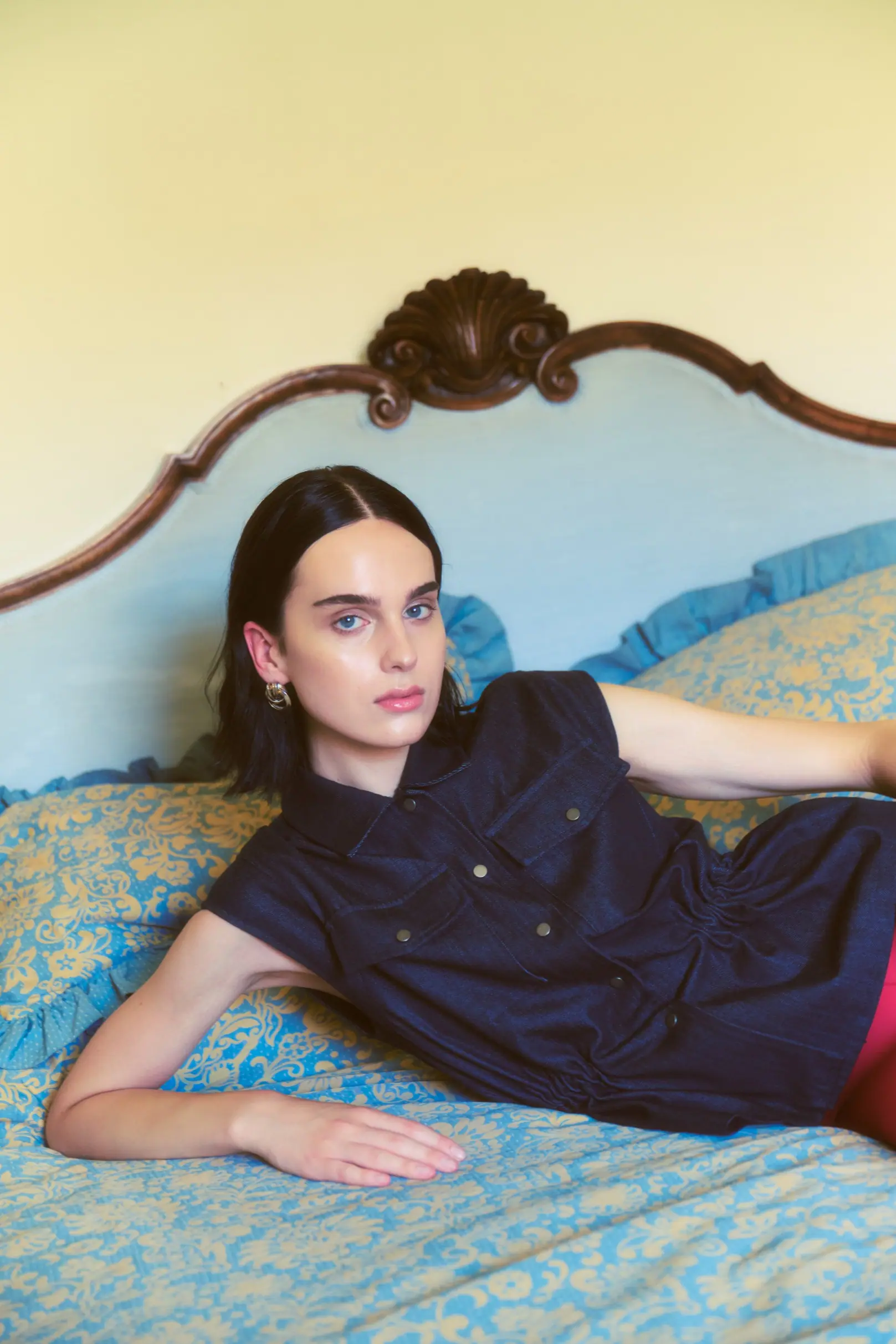 A woman reclining on an antique sofa in a softly draped dark dress, sunlit Tuscan interior.
