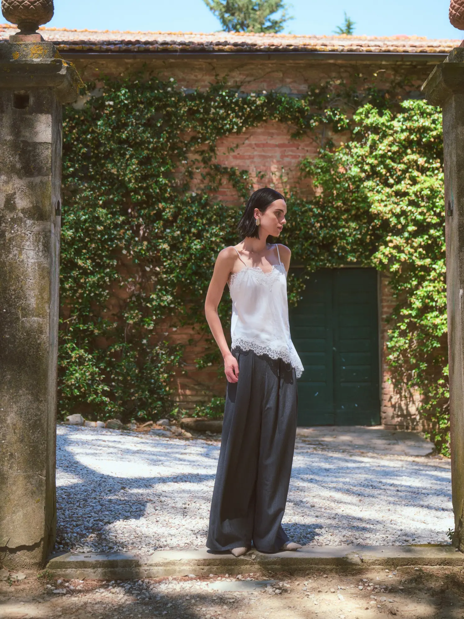 A woman resting on a vintage armchair set among the gardens, unhurried elegance.