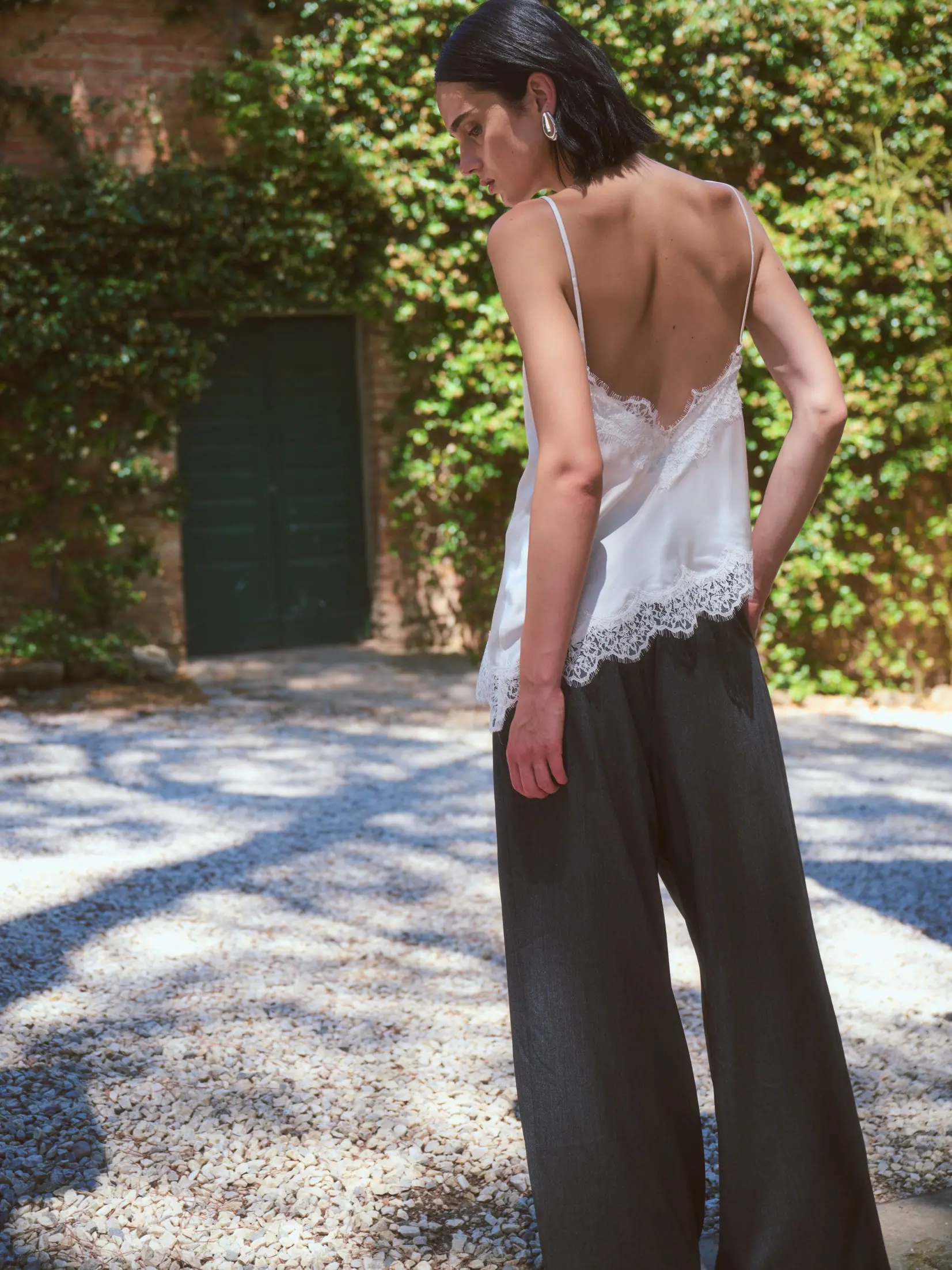 A woman standing in a flowering Tuscan garden in a fluid silhouette.