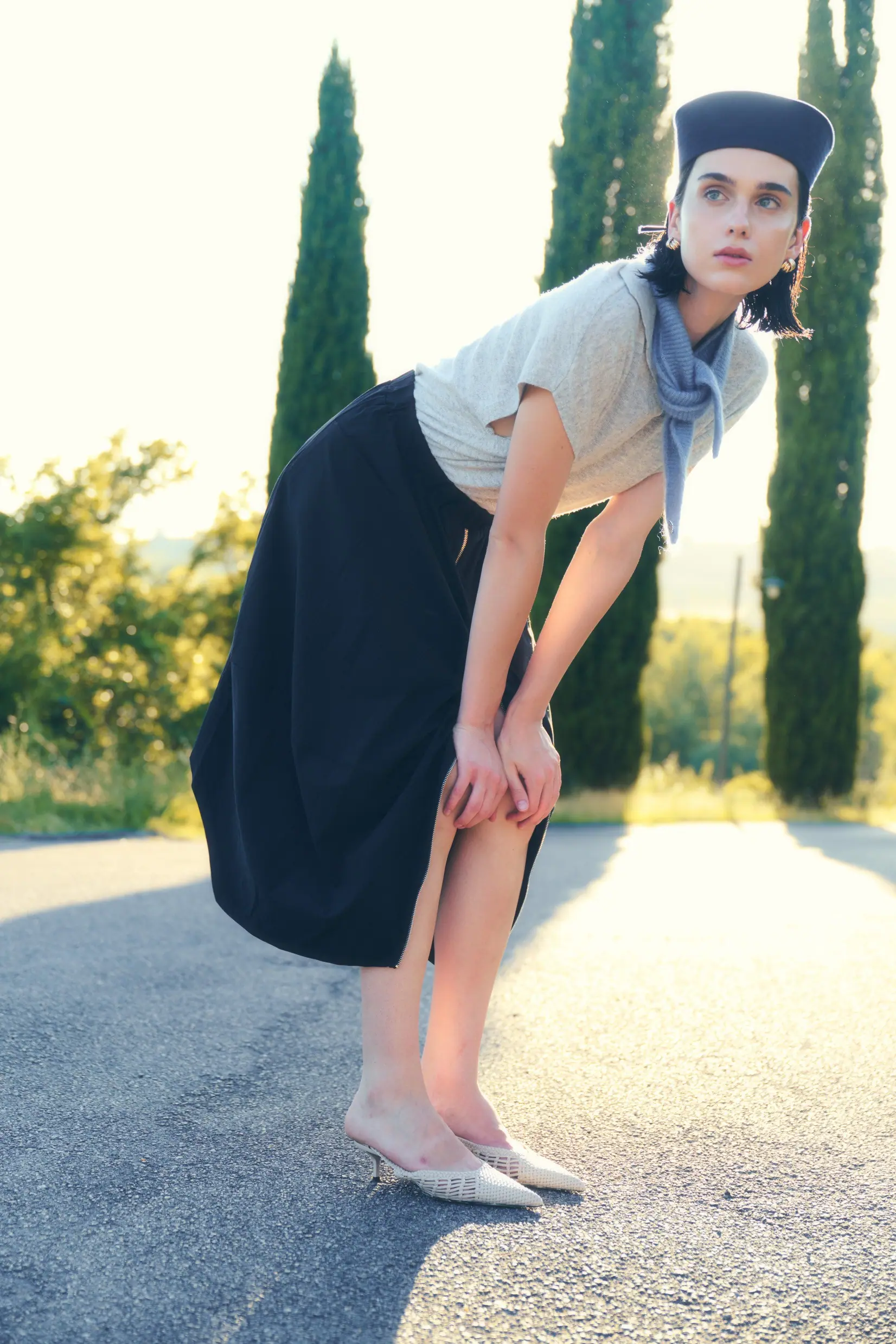 A full-length figure on a cypress-lined road, echoing the cover.